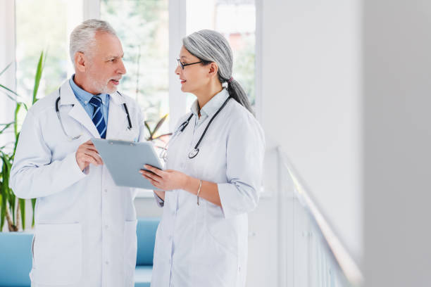 istock In hospital two doctors discussing in hallway while using clipboard 1271327204
