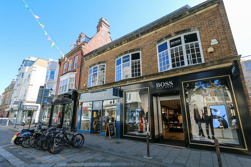 BOSS Meanswear Store on East Street in Brighton, England, epitomised by the Hugo Boss brand. Other stores are in the background and several bicycles in the foreground.