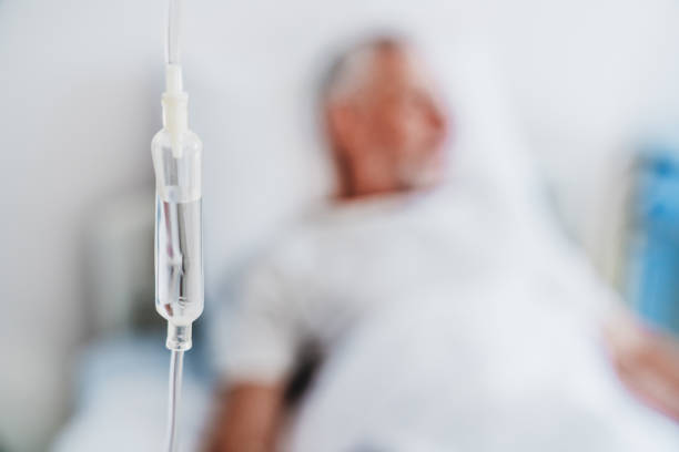 Close up shot of medicine in and iv drip and patient on background in hospital room Close up shot of medicine in and iv drip and patient on background in hospital room chemotherapy drug stock pictures, royalty-free photos & images