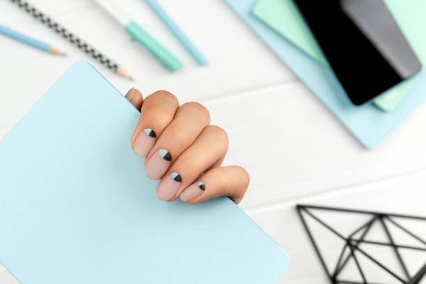 istock Groomed womans hand with creative nail design holding note pad 1271329118
