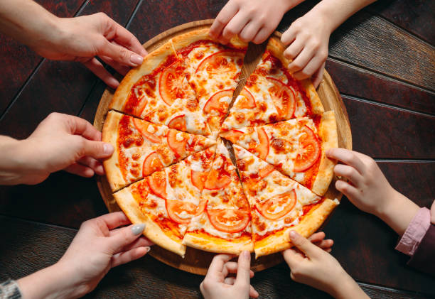 istock Hands taking pizza slices from wooden table, close up view. 1271332484
