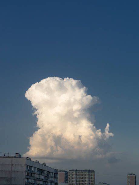 istock Single cumulus cloud over cityscape against blue sky. 1271332875