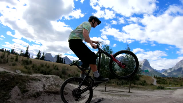 Young adults take bike jumps in mountain park