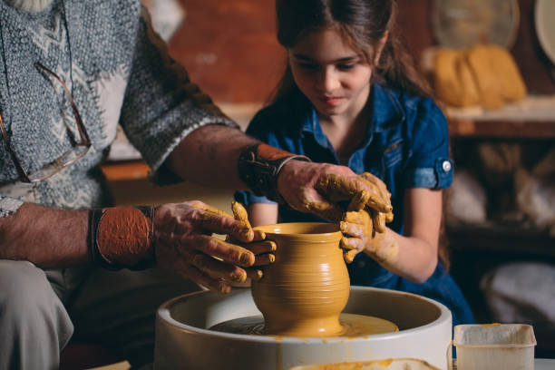 istock Pottery workshop. Grandpa teaches granddaughter pottery. Clay modeling 1271334010