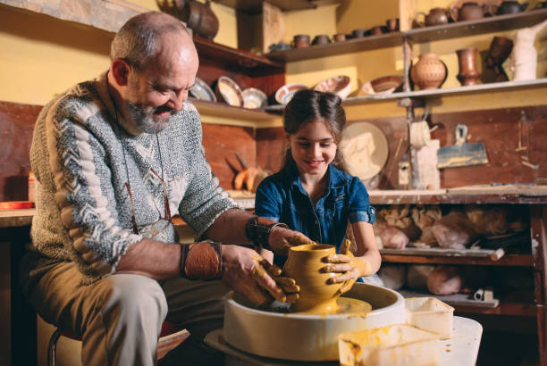 istock Pottery workshop. Grandpa teaches granddaughter pottery. Clay modeling 1271334107