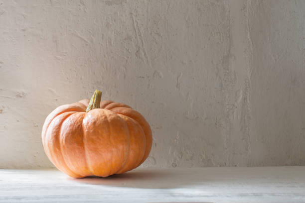 istock orange pumpkin on wooden table on background white wall 1271335877