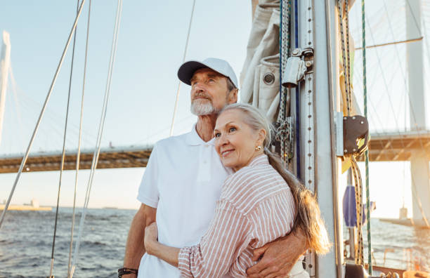 istock Affectionate senior couple hugging together and looking into the distance while standing on a yacht 1271337013