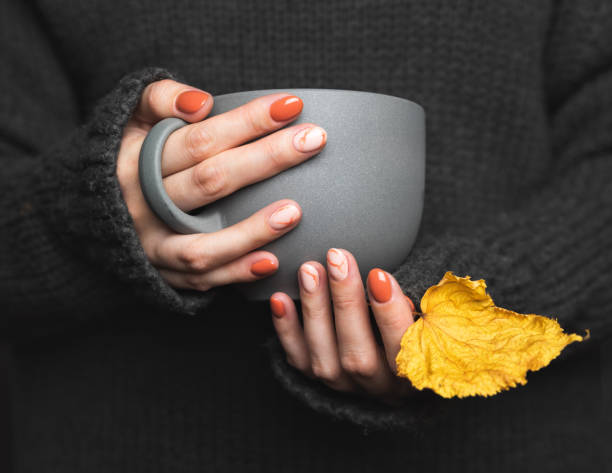 la mujer sostiene una taza de té caliente. suéter de punto gris - fingernail acrylic women beauty fotografías e imágenes de stock