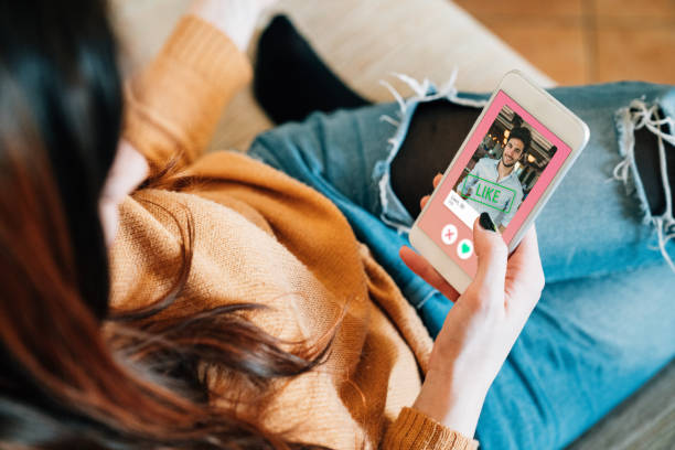 Young adult woman swiping on an online dating app Young adult woman swiping on an online dating app. She's using her smart phone on the sofa at home. couples dating stock pictures, royalty-free photos & images