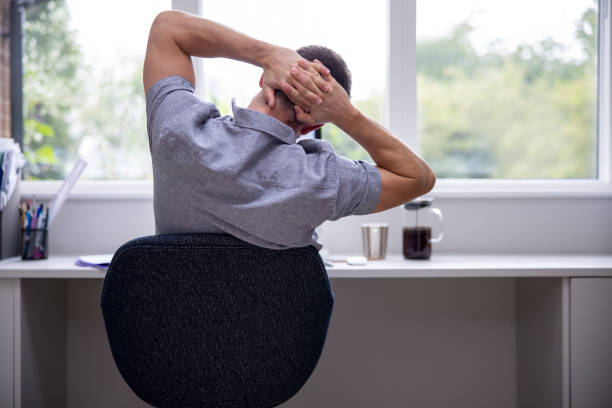 istock Rear View Of Man Working From Home On Computer  In Home Office Stretching At Desk 1271341245