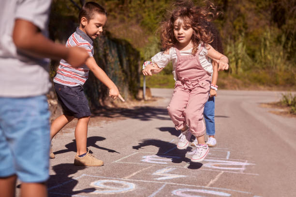 Group of kids having fun playing hopscotch on street Group of multi-ethnic happy kids having fun playing hopscotch on outdoors street schoolyard stock pictures, royalty-free photos & images