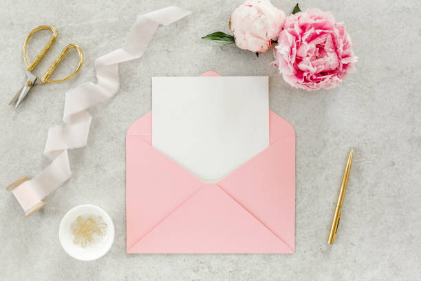 istock Mockup invitation, blank paper greeting card, pink envelope and peonies on gray stone table. Flower background. Flat lay, top view 1271345392