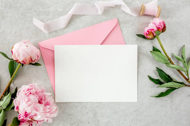istock Mockup invitation, blank paper greeting card, pink envelope and peonies on gray stone table. Flower background. Flat lay, top view 1271346034