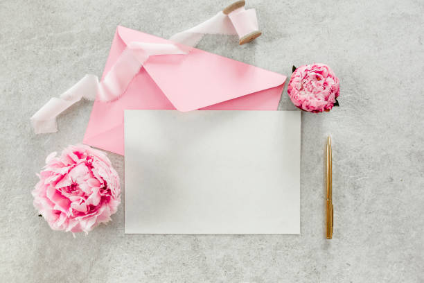 istock Mockup invitation, blank paper greeting card, pink envelope and peonies on gray stone table. Flower background. Flat lay, top view 1271346177