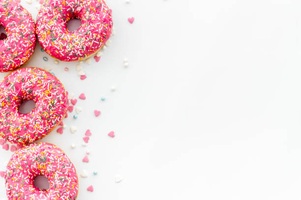 istock Pink berry donuts flat lay, top view. Glazed and sprinkles doughnuts 1271346857