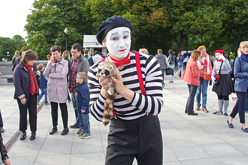 Moscow, Russia - September 10, 2016: A male mime with a soft raccoon toy at the Bright people festival in Gorky Park on city Day in Moscow