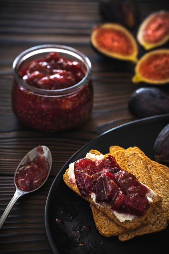 Figs jam homemade with fig fruits cheese and bread toast slice on moody dark rustic wood