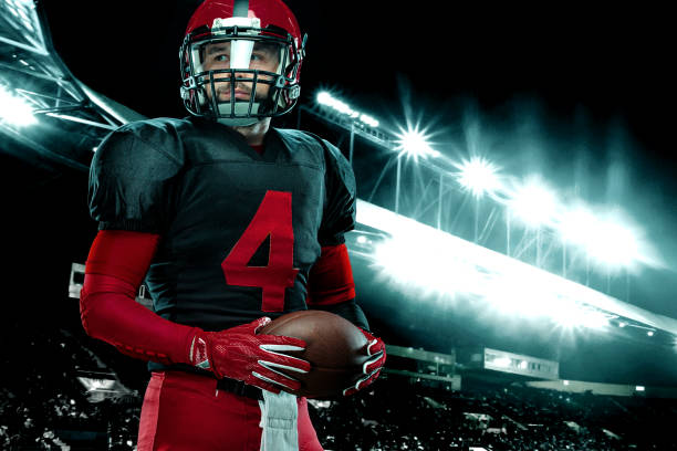 アメリカンフットボール選手、スタジアムの背景に赤いヘルメットを持つアスリートスポーツマン。スポーツとモチベーションの壁紙。 - american football sport university football player ストックフォトと画像