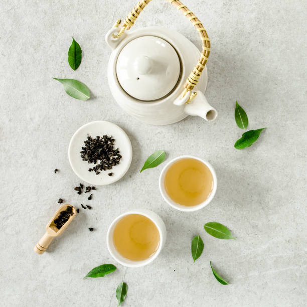 istock Herbal tea with two white tea cups and teapot, with green tea leaves. Flat lay, top view. Tea concept 1271359476