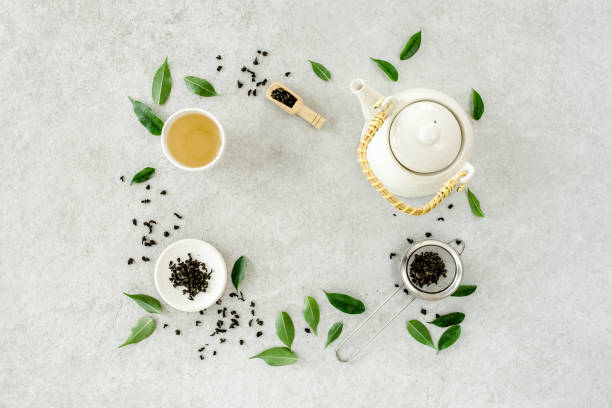 istock Herbal tea with two white tea cups and teapot, with green tea leaves. Flat lay, top view. Tea concept 1271367332