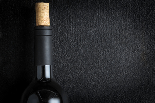 A bottle of red wine with wine cork on black Background, copyspsce. Winemaking  concept\