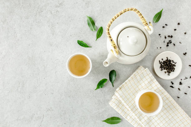 istock Herbal tea with two white tea cups and teapot, with green tea leaves. Flat lay, top view. Tea concept 1271369837