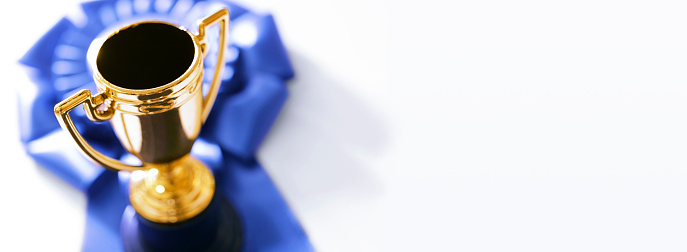 A trophy and a blue ribbon photographed with a very shallow depth of field