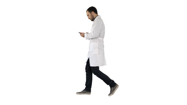 istock Male doctor walking and using mobile phone on white background 1271372743