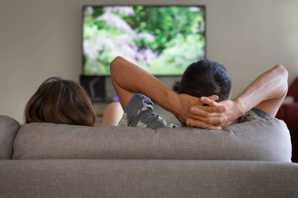 un couple regardant la télévision et se détendre à la maison. - television boredom men sofa photos et images de collection