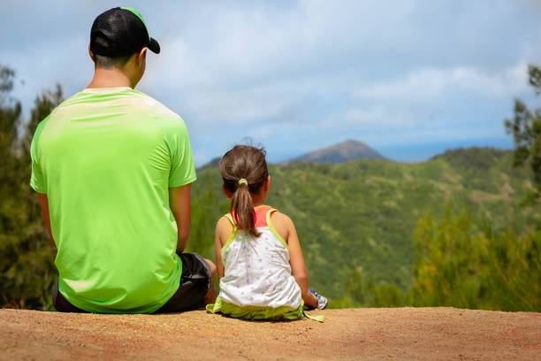 Father and little kid sitting together in nature. A young father enjoys a view with his daughter single father stock pictures, royalty-free photos & images