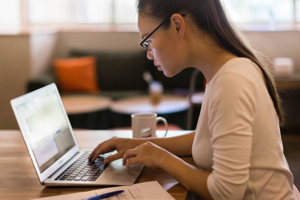 Woman working on her computer at home. Online business. Business woman online at work, in a home office setting. A student studying online classes. application form stock pictures, royalty-free photos & images