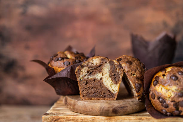 istock Soft and moist chocolate muffins with dark chocolate drops in wooden box, rustic table. Homemade baked twisted cupcakes. 1271382573