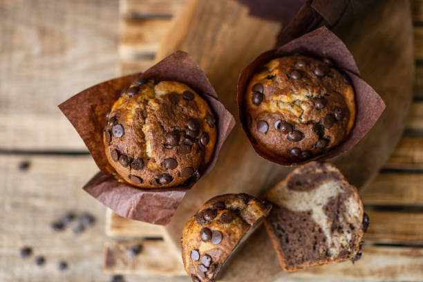 Soft and moist chocolate muffins with dark chocolate drops in wooden box, rustic table. Homemade baked twisted cupcakes.