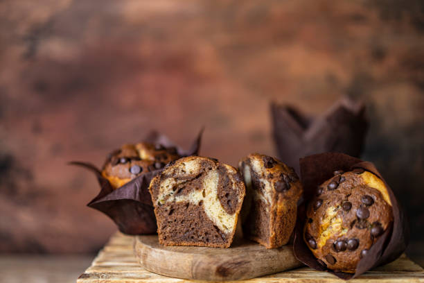 istock Soft and moist chocolate muffins with dark chocolate drops in wooden box, rustic table. Homemade baked twisted cupcakes. 1271382588
