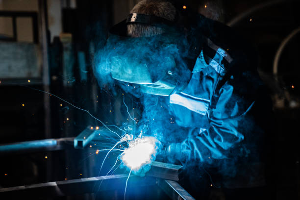 Engineer work day Senior man welding a metal construction. He is dressed in full protective suit. welding helmet stock pictures, royalty-free photos & images