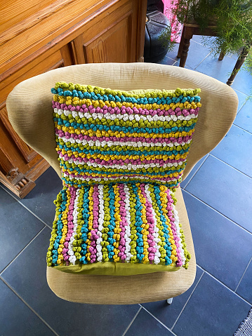 Top view on empty wing back chair with colorful cushions from seventies in german living room - Germany