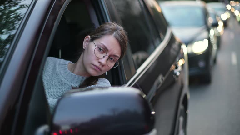 Close-up of a young woman looking through a car window in a traffic jam