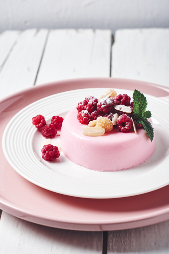 Pink panna cotta dessert with fresh raspberries.