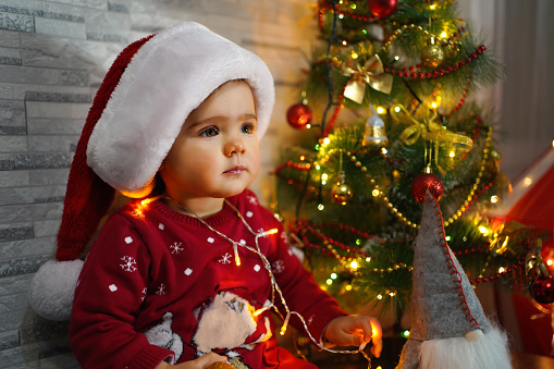 Baby girl in a red hat of Santa Claus in a Christmas decorations