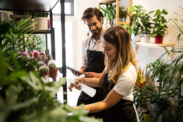 floristas que trabalham em floricultura própria verificando plantas - florist flower market flower store - fotografias e filmes do acervo