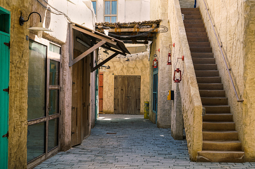 Scene in the Al Fahidi historic area of Dubai, UAE, which depicts the traditional styles of neighborhoods of the past, with colorful doors and traditional architecture constructed from stone, gypsum, teak, and sandalwood.
