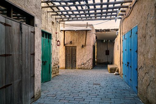 Scene in the Al Fahidi historic area of Dubai, UAE, which depicts the traditional styles of neighborhoods of the past, with colorful doors and traditional architecture constructed from stone, gypsum, teak, and sandalwood.