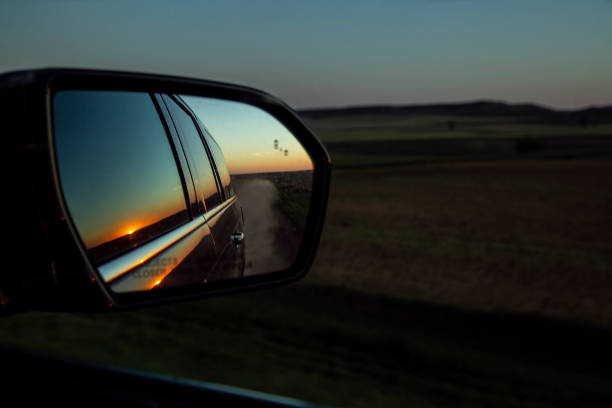 sunrise view in sideview mirror on dirt road - dirtroad imagens e fotografias de stock