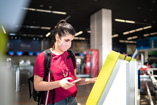 Woman doing checking in at the airport wearing face mask