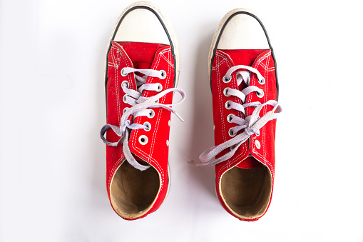 red sneakers with lacing on white background, closeup, top view