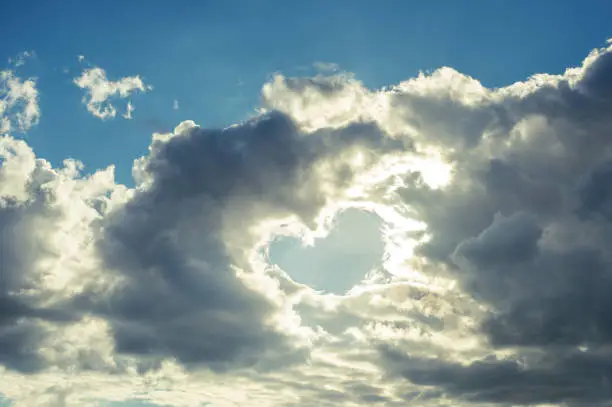 Clouds in the form of a heart on a background of blue sky and sunlight, card for valentine's day