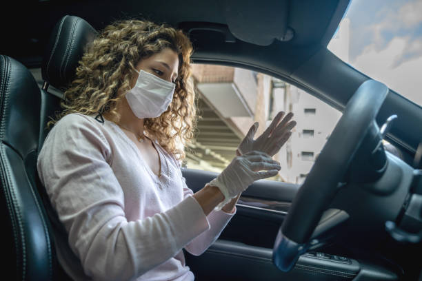 istock Woman in a car wearing a facemask while and putting on her gloves 1271409729