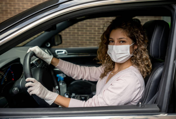 Beautiful woman wearing a facemask and gloves while driving a car Portrait of a beautiful woman wearing a facemask and gloves while driving a car to avoid the coronavirus â COVID-19 pandemic concepts car rental covid stock pictures, royalty-free photos & images
