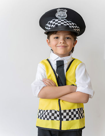 Happy boy dressed as a police officer with arms crossed over a white background