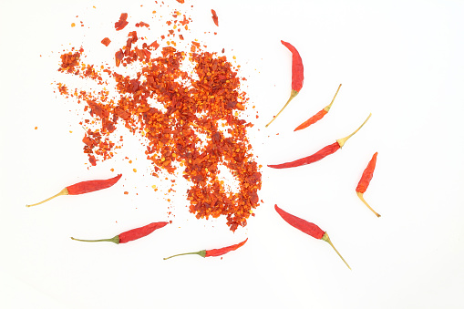 red dried crushed hot chili peppers and chili flakes or powder isolated on white background, healthy turkish spice